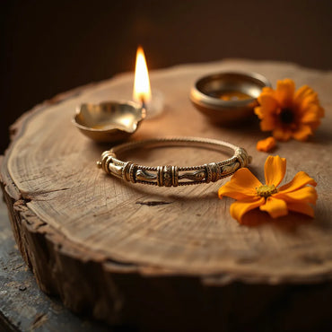 A spiritual bracelet resting on wood with a small diya and marigold flowers beside it
