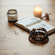 Delicate religious necklaces and bracelets arranged beside a Bible on a warm wooden table