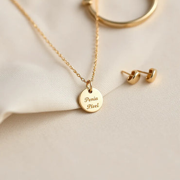 Delicate pendant necklace with engraved-style details on a soft neutral background